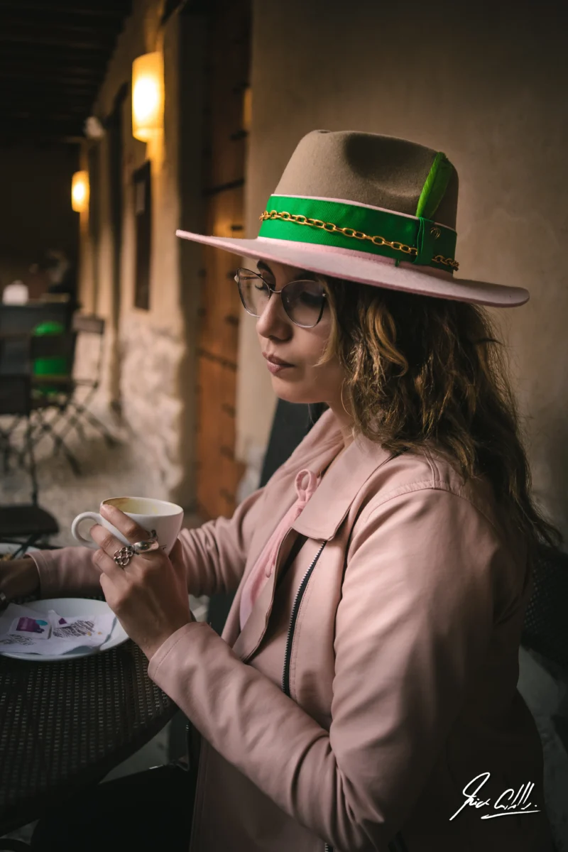 Karla Betancourth, cofundadora de Big Apple Creative Studio, disfrutando un café con sombrero elegante en una terraza de estilo rústico en Quito, Ecuador.